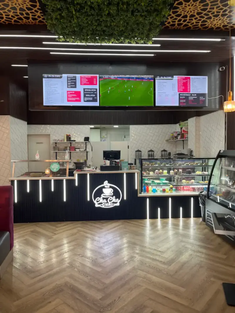 The Cha Cha Chai counter with screens above it and the dessert cabinets beside the till
